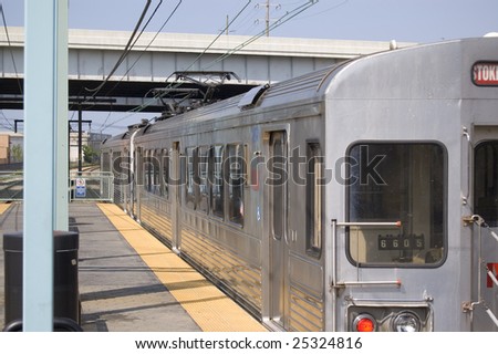 Silver commuter train at station.