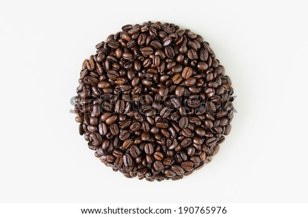 A perfectly round circular heap of coffee beans isolated against a white background.