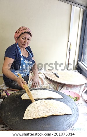 LONDON, UK - JUNE 16, 2014:  Turkish woman cooks traditional Turkish pastry at a bakery\'s front window in London.