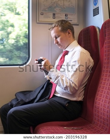 LONDON, UK - JUNE 26, 201:  Man with his tablet pc returning home after work on a London overground train.