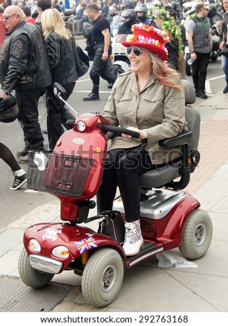 HASTINGS, ENGLAND - MAY 4, 2015:  Female spectator drives her disable car during Jack in the Green festival in Hastings, UK.