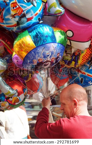 HASTINGS, UK - MAY 04, 2015: Balloon seller holds a group of balloons to sell on the street during the Jack the Green Festival in Hastings, UK