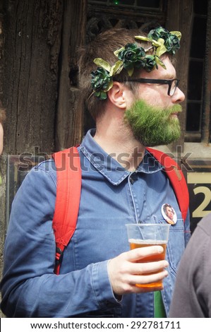 HASTINGS, UK - MAY 04, 2015: Man with green painted beard and garlands on his head drinks beer during the Jack in the Green Festival in Hastings, UK.