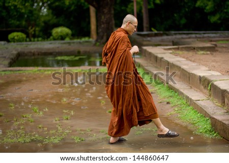 ANGKOR WAT, CAMBODIA - CIRCA OCTOBER 2011: Unidentified monk walking for prays during rain in Angkor Wat. All temples in Ankgor complex were completely flooded after heavy rains in Cambodia in 2011.