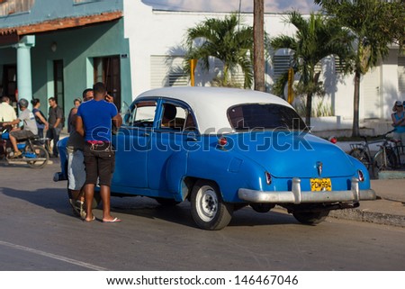 VINALES - FEBRUARY 4: Two men talk with the driver of classic car parked on the street on February 4, 2013 in Vinales. These old and classic cars are an iconic sight of the Cuba island