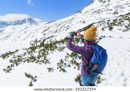 Young lady in colorful clothes takes picture of a mountain's panorama