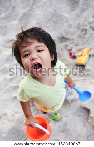 a little boy plays in the sand pit