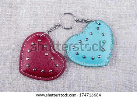 two hearts of leather connected with chain lying on rough textile