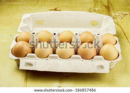 ten chicken eggs in the container on wood, background with space for text