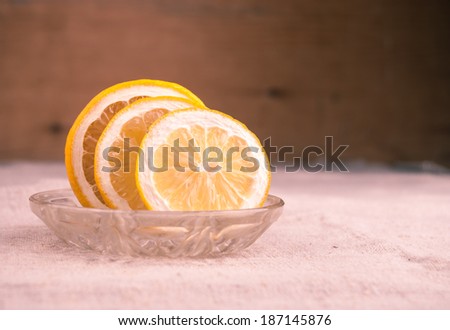 Macro shot of lemon cut to slices on little plate on table covered with rough textile