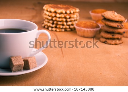 white china cup with brown sugar, cookies, and muffins on table