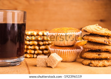Glass cup with brown sugar, cookies, and muffins on table