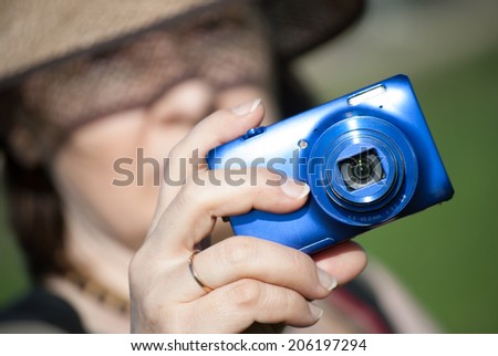 woman with compact digital photocamera. Blurred face.
