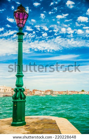 Green lantern on Giudecca island in Venice, Italy. In the background is a view on Venetian Lagoon with cityscape of Venice and beautiful blue sky.