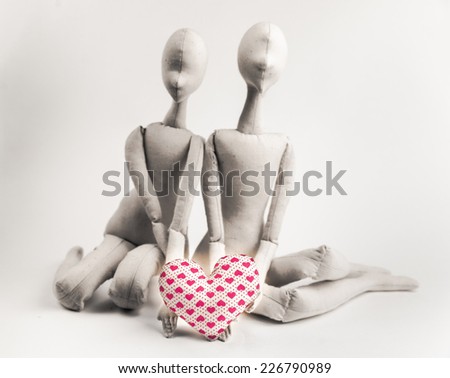 Two handmade textile dolls holding red heart. Image of love, affection.