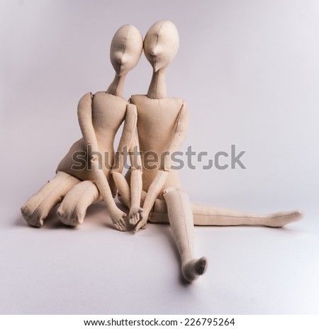 Two handmade textile dolls sitting together. Image of love, affection.