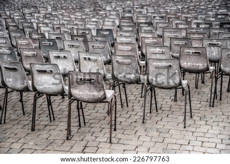 Rows of empty plastic seats on stone pavement, outdoor setting