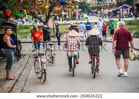 HOI AN, VIET NAM - FEBRUARY 8, 2015: Unidentified tourists and vietnam citizens on bycicles are on a decorated street of Hoi An ancient city, Da Nang province, Vietnam.