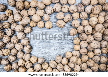 Plenty of walnuts on wood with space for text in centre. Image of harvest, autumn, and vegetarian food. Raw food texture. Rural texture background.