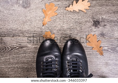 Men\'s shoes for autumn on rustic wooden background with wethered autumn leaves. Blue boots on the ground.