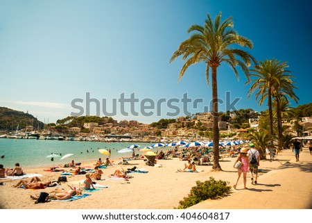 View of the beach of Port de Soller with people lying on sand and the old buildings visible in background, Soller, Balearic islands, Spain.