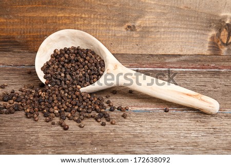 black peppercorns in wooden spoon