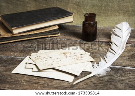 old letters, books,  an ink bottle and a quill on vintage wood