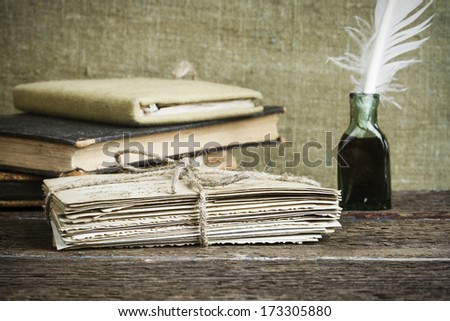 old letters, books and an ink bottle with a quill on vintage wood