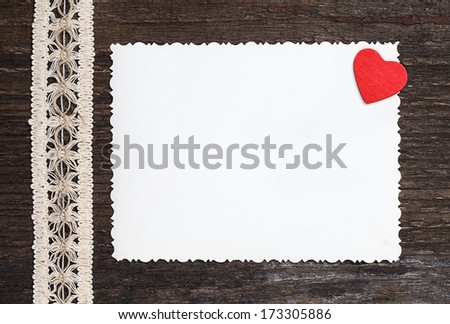 old card on aged wood decorated with wooden heart and vintage ribbon
