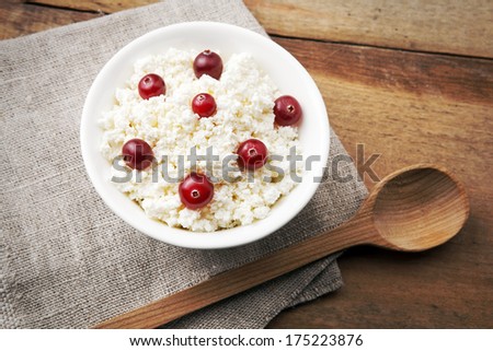 porridge with cranberries in white bowl with wooden spoon on linen tablecloth on wooden table