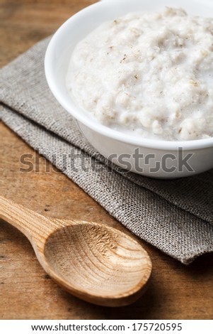 bowl of porridge and wooden spoon on linen cloth on aged table
