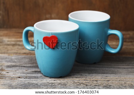 two blue cups with red heart on grunge wooden vintage table