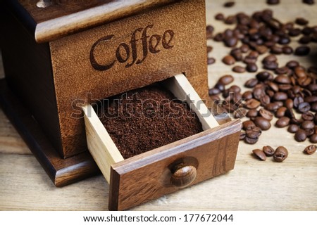 ground coffee  in vintage coffee grinder and roasted coffee beans on wooden table