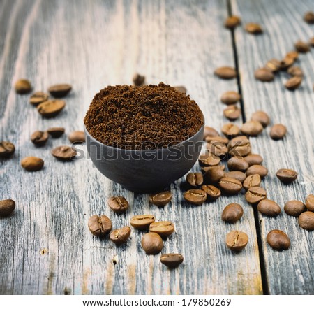 ground coffee in small blue cup and coffee beans on wooden table