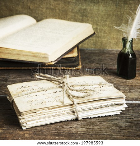 old letters, books, an ink bottle and a quill on vintage wood