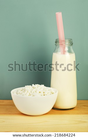 dairy products: school milk bottle with a straw and cottage cheese on wooden table, vintage look