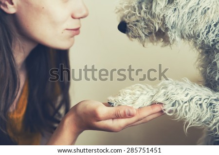 woman\'s hand and dog\'s paw