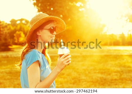 smiling young girl, walking in park holding drink, sunny rural landscape