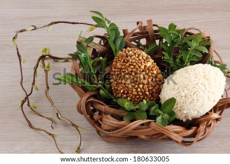 Easter decorations / cards hand-decorated Easter eggs an unusually covered in spices and couscous with boxwood in a nest made of rattan on a wooden background / on the table with willow sticks