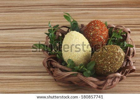 Easter decorations / cards hand-decorated Easter eggs covered in spices, couscous, rice and buckwheat with boxwood in a nest made of rattan on a wooden background / on the table