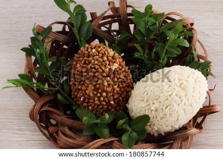 Easter decorations / cards hand-decorated Easter eggs covered in rice and buckwheat  with boxwood in a nest made of rattan on a wooden background / on the table