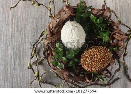 Easter decorations / cards hand-decorated Easter eggs an unusually covered in rice and buckwheat with boxwood in a nest made of rattan on a wooden background / on the table with willow sticks