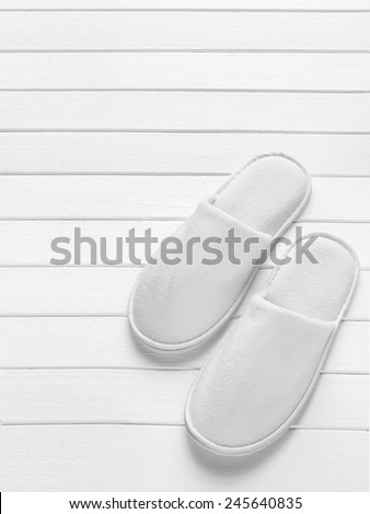 White hotel / home/ spa / wellness slippers with towel on light wood desk with space for text - summer sauna time