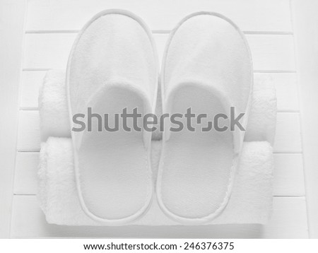 White hotel / home/ spa / wellness slippers with rolled towels on light wooden desk - summer sauna time