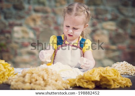 The girl smashing an egg into the flour for pasta.