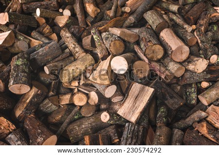 Firewood in a piece of wood stored on the stack, hands holding a piece of firewood