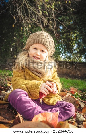 Beautiful girl, smiling blonde plays with the autumn leaves