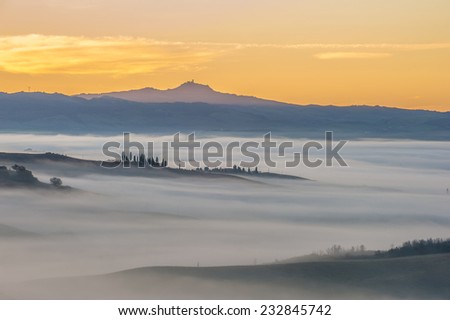 Fantastic Tuscan landscape in the fog and the light of the rising sun.