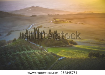 Fantastic Tuscan landscape in the fog and the light of the rising sun.