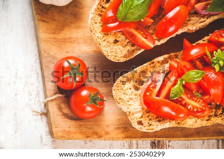 Italian starter, bruschetta with Sicilian red fresh tomato on a wooden background